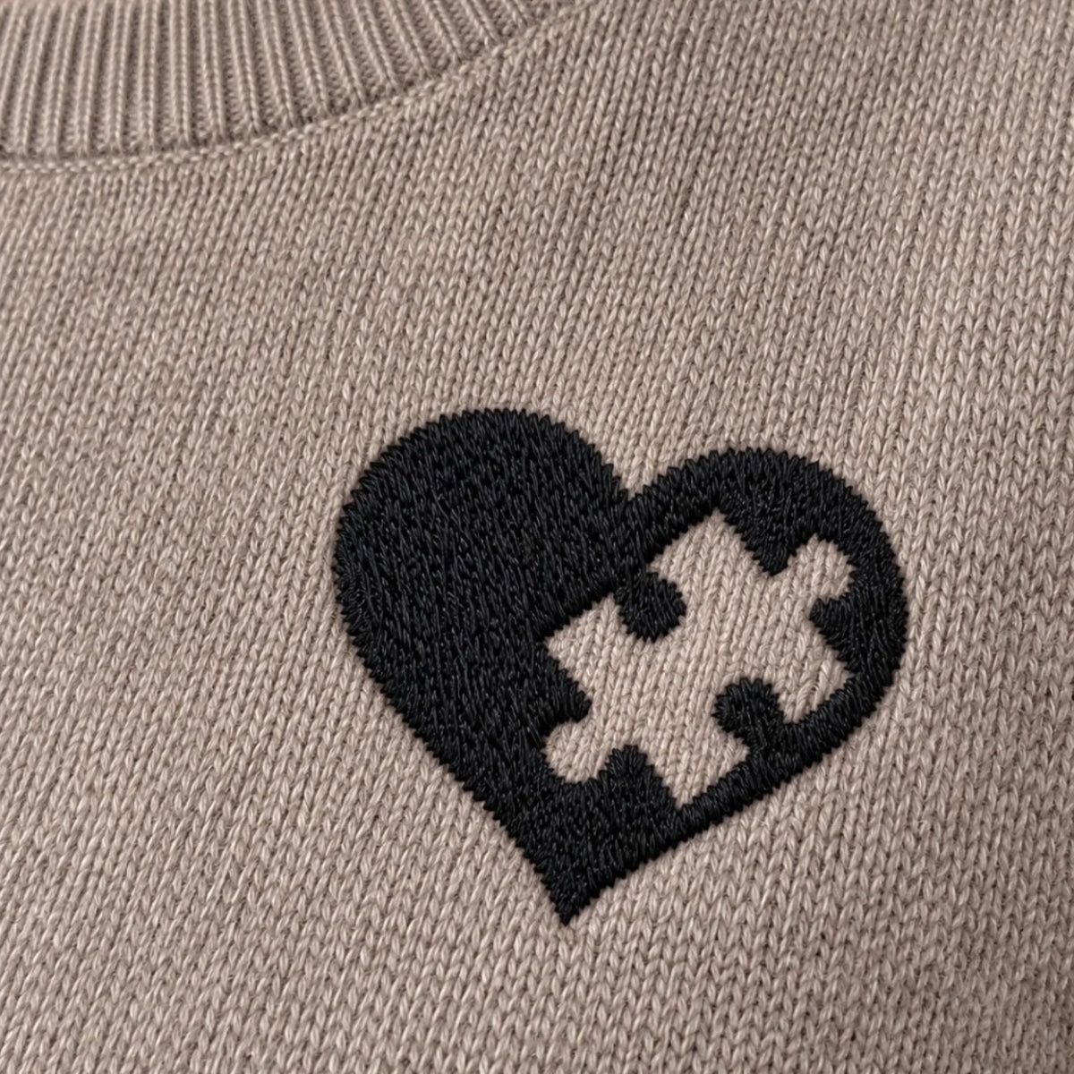 Detail des gestickten Puzzle-Herzens auf dem Damen-Pullover